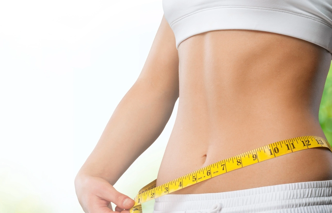 Close-up image of a woman's waist measuring Weight Loss with a yellow tape in Evans, GA | Sumner Aesthetics
